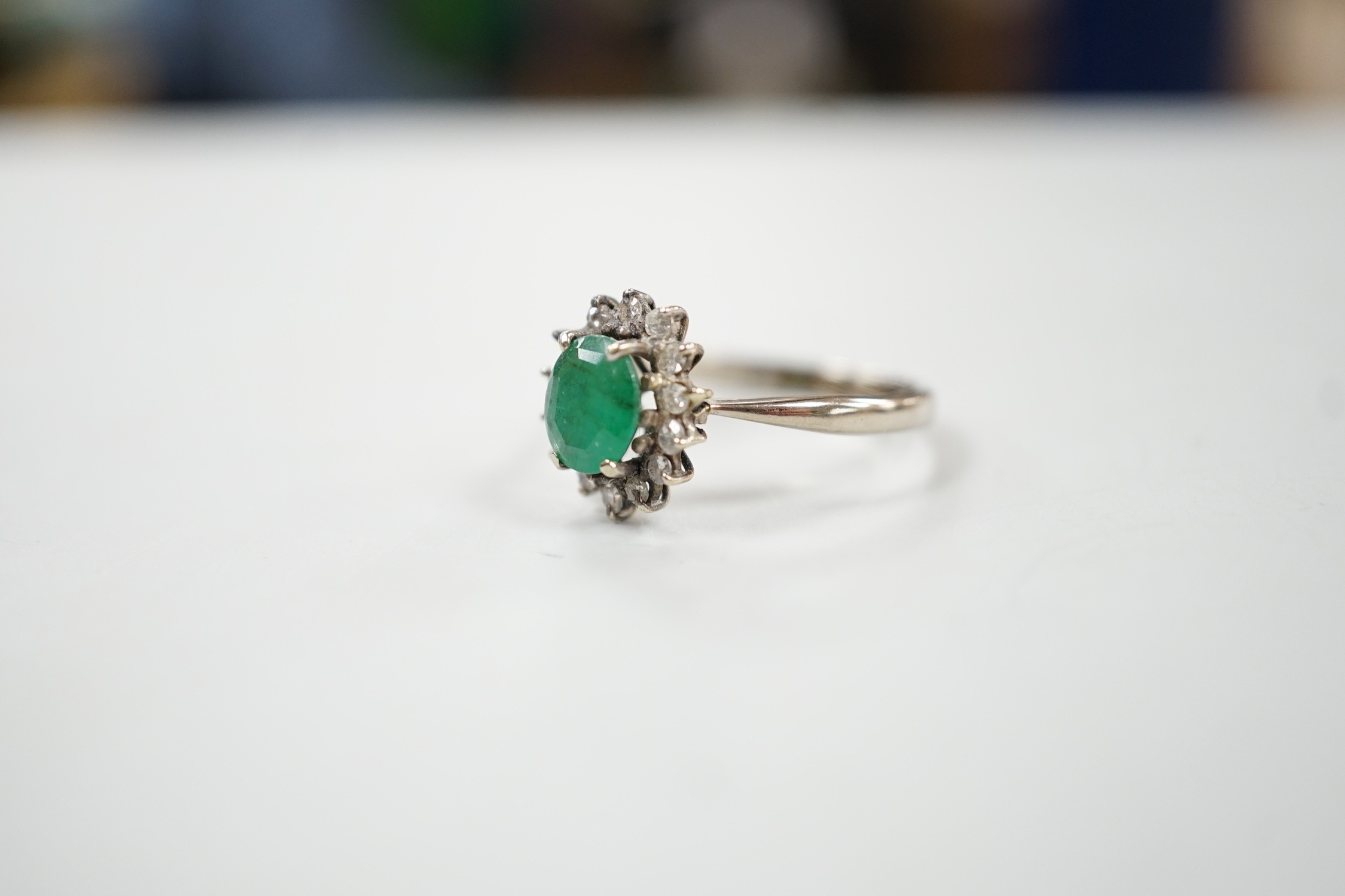 An 18ct, emerald and diamond set oval cluster ring, size O/P, gross weight 3.2 grams.